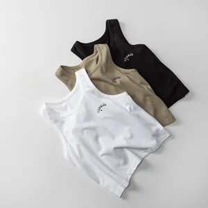 Dettaglio di tre canotte per bambini in cotone a coste nei colori bianco, kaki e nero stampato