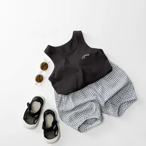 Flat lay of a kid's summer cotton set with a black tank top and plaid shorts