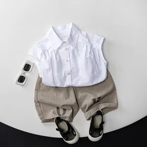 Tenue d'été pour enfants avec chemise sans manches en coton blanc et short kaki sur tapis