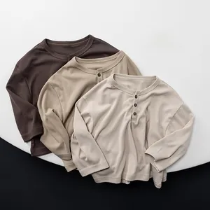 Detailed close-up of three cotton Henley shirts for kids in earth tones with wooden buttons