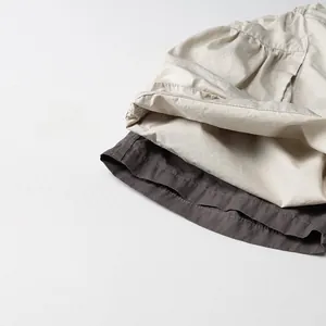 Détail de la texture du tissu des shorts cargo en coton beige et gris foncé