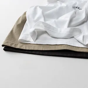 Dettaglio di tre canotte in cotone sovrapposte in bianco, kaki e antracite con stampa estiva