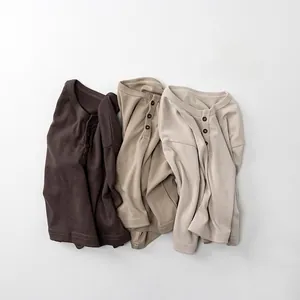 Detailed view of three cotton Henley shirts in brown, khaki, and cream tones with buttons
