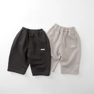Dettaglio dei pantaloni sportivi in cotone per bambini in grigio antracite e beige con elastico