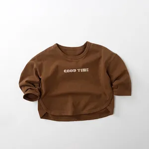 Détail d'un t-shirt enfant en coton marron foncé avec imprimé GOOD TIME et ourlet arrondi