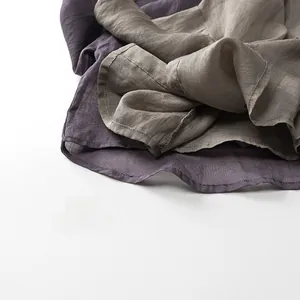 Gros plan détaillé sur la texture du lin et les coutures fines en violet et taupe