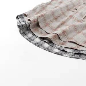 Detailed macro view of kids plaid shirts showing cotton linen texture and curved hem