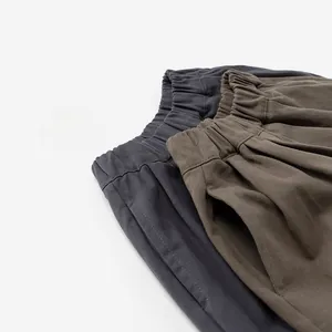 Detail of stacked cotton wide-leg pants in dark grey, blue, and coffee brown colors