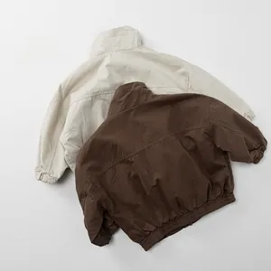 Detail of cotton kids utility jackets in beige and brown with elastic cuffs and hem