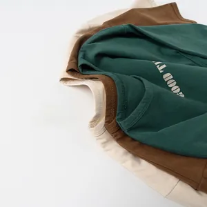 Détail de t-shirts en coton empilés en vert, marron et beige avec col rond