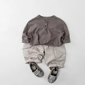 Flat lay of cotton Henley shirt, beige cargo shorts, and striped shoes for kids outfit