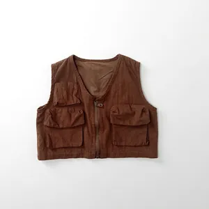Detail of a brown cargo vest for kids featuring functional pockets and a metal zipper