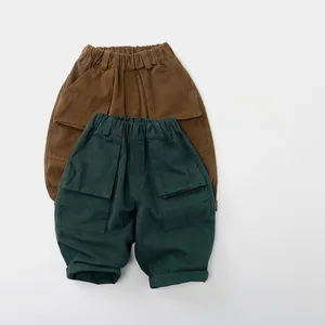Détail de pantalons cargo pour enfants en marron et vert foncé avec grandes poches