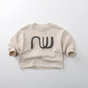 Détail d'un sweat-shirt enfant crème avec imprimé NW gris et finitions poignets côtelés