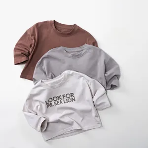 Detail von drei Baumwoll-Kinder-T-Shirts in Rostrot, Hellgrau und Beige-Tönen