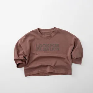 Detail eines braunen Langarmshirts aus Baumwolle für Kinder mit Motivdruck auf Stoff