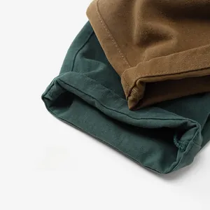 Gros plan détaillé des pantalons en coton vert foncé et caramel avec coutures de qualité