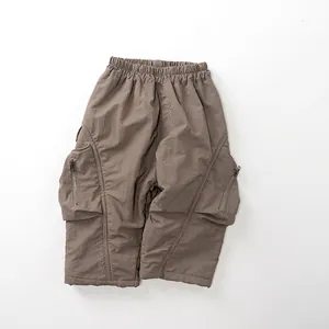 Detail of kids cargo pants with elastic waistband and large functional metal zipper pockets