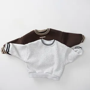 Flat lay of brown and grey fleece-lined sweatshirts with Sunday print and striped cuffs