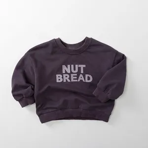Detail of deep purple kids sweatshirt with NUT BREAD print and ribbed cuffs