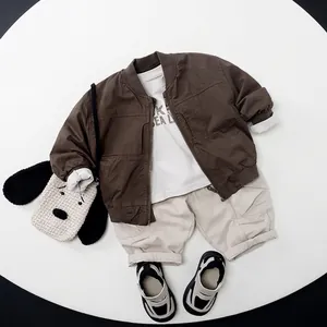 Flat lay of boy's autumn dark brown jacket with white t-shirt and beige cargo pants