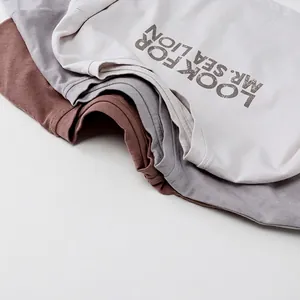Drei gestapelte Baumwoll-T-Shirts in Ziegelrot, Grau und Creme mit Sea Lion-Aufdruck