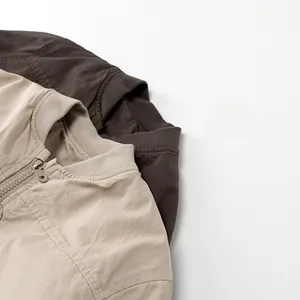 Close-up of beige and brown kids jackets with ribbed collar and metal zipper details