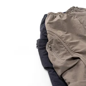 Detail of elastic waistband and metal zipper pockets on gray and khaki cargo pants