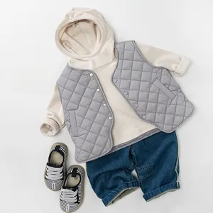 Flat lay of kids beige hoodie, grey quilted vest and denim jeans outfit set