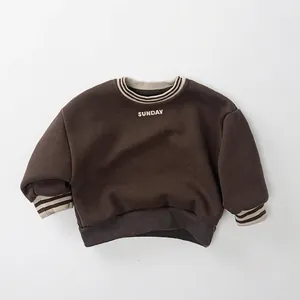 Close-up of brown fleece sweatshirt showing ribbed cuffs with beige stripes and Sunday print