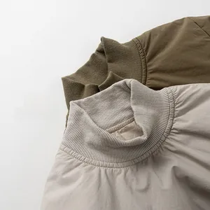 Detail of ribbed knit turtleneck collars on toddler jackets in olive and beige colors