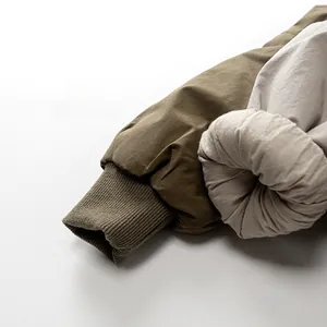 Detail shot of olive green ribbed knit cuffs and beige quilted down jacket sleeves