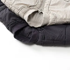 Close-up of quilted kids' vests in beige and dark grey with ribbed collar and zipper
