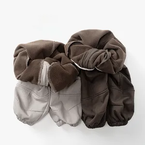 Dettaglio della fodera in pile spesso dei pantaloni invernali per bambini in beige e caffè