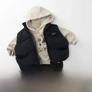 Outfit per bambini con felpa beige, gilet nero imbottito e pantaloni di velluto