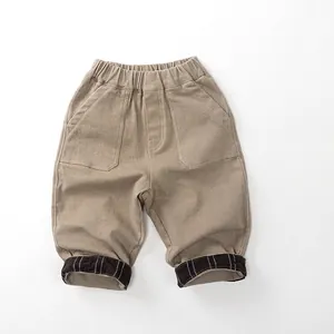 Detail of children khaki trousers featuring elastic waist and striped cuff lining