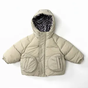 Détail de la doudoune beige pour enfants avec doublure léopard et poches rondes