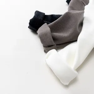Detailed close-up of cotton knit textures in black, dark grey, and creamy white tones