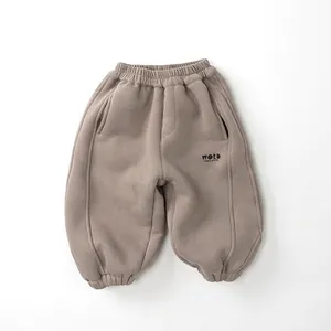 Detail of kids warm fleece jogger pants in light brown featuring elastic waist and word print