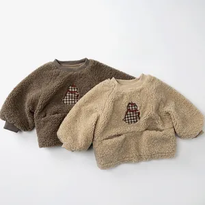 Détail de pulls en polaire sherpa pour enfants avec broderie ours en marron et beige