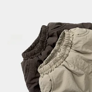 Detail of elastic waistbands on thick padded winter pants in brown and beige colors