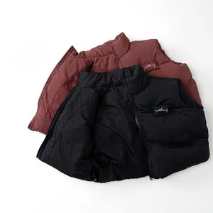 Dettaglio di gilet invernali per bambini con collo alto e ricamo in nero e rosso scuro