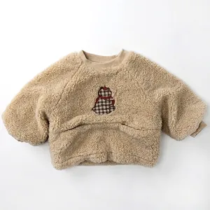 Détail d'un sweat en polaire beige avec broderie d'ours à carreaux pour enfant