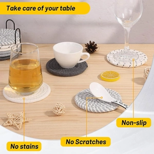 Set of woven cotton rope coasters with black metal holder on a wooden table surface