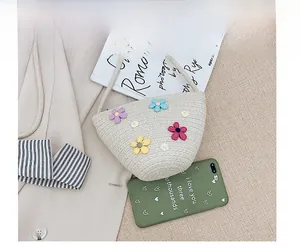 Vue détaillée du sac seau en paille fait main avec fleurs colorées et bandoulière fine