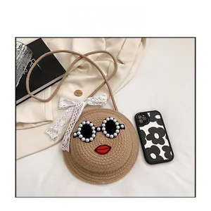 Detailed shot of round straw bag with pearl sunglasses and red lips embroidery