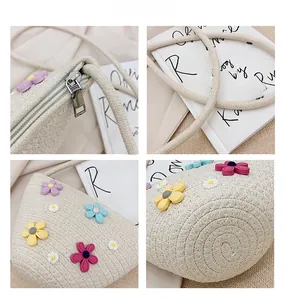 Détail d'un sac en paille beige avec broderies florales colorées et fermeture éclair