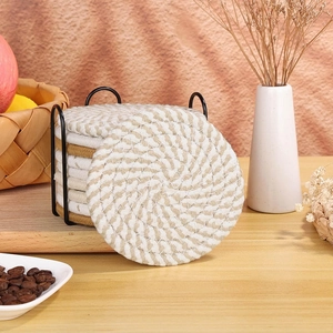 Detail of round woven cotton coasters with a black metal storage rack on a wooden table