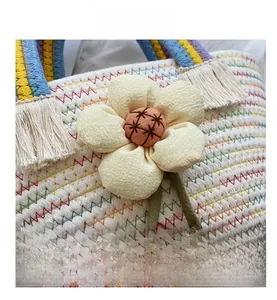 Dettaglio borsa di paglia intrecciata con grande fiore in tessuto e manico colorato