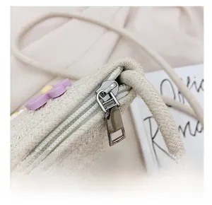 Détail de la fermeture éclair en métal argenté et du tissu tissé du sac en paille